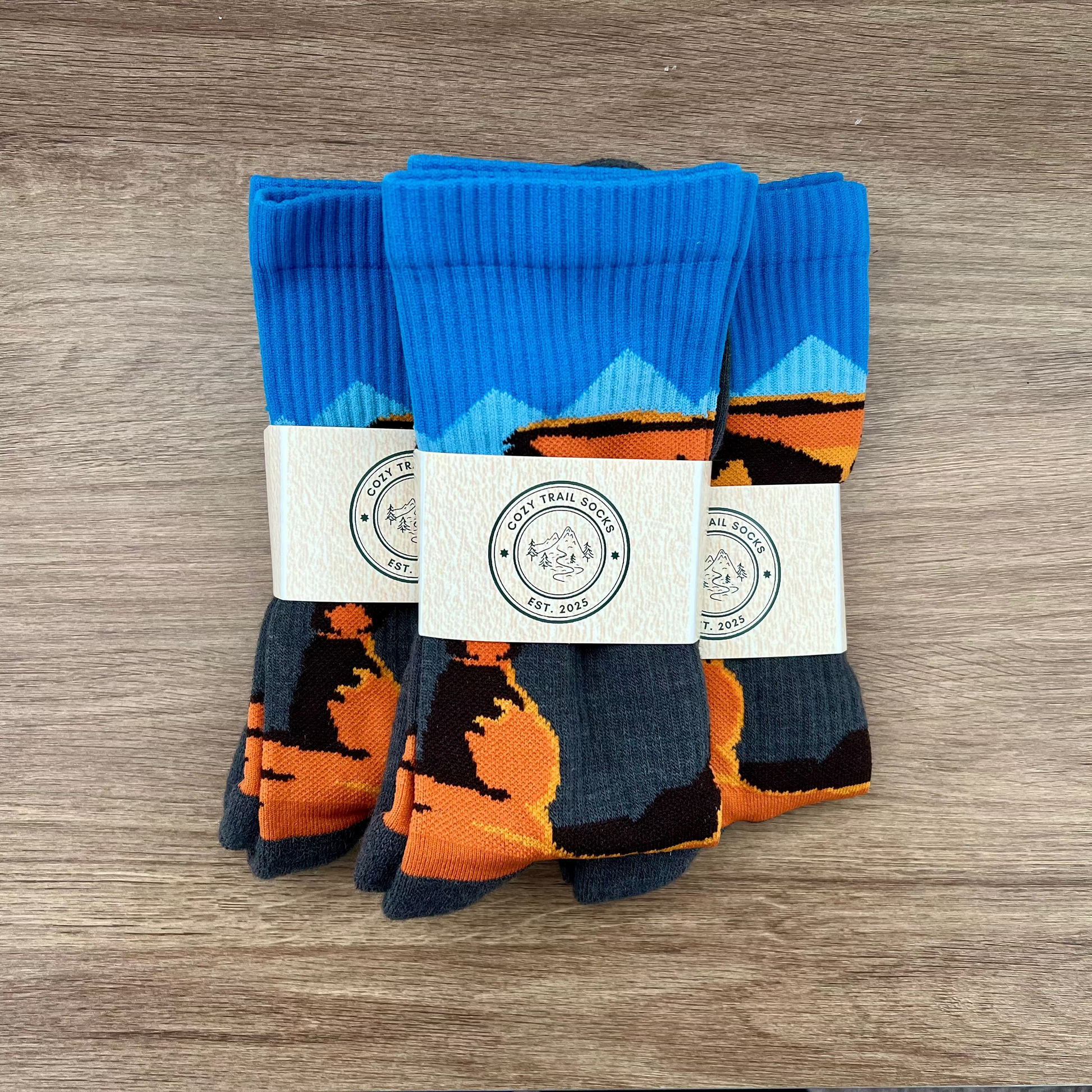 Three pairs of socks with Delicate Arch design on a wooden surface